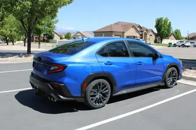 A blue subaru wrx sti is parked in a parking lot.