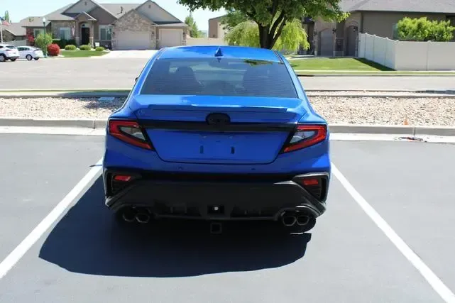 A blue car is parked in a parking lot in front of a house