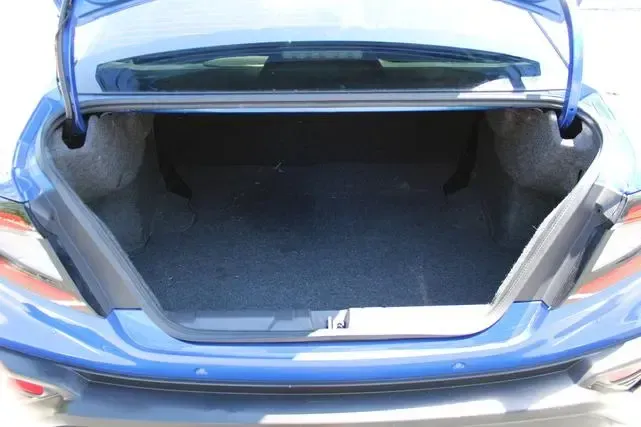 The trunk of a blue car is open and empty.