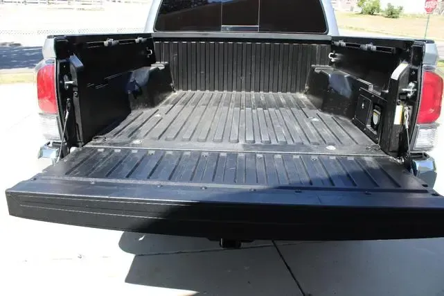 The back of a truck with the bed open is parked on the side of the road.