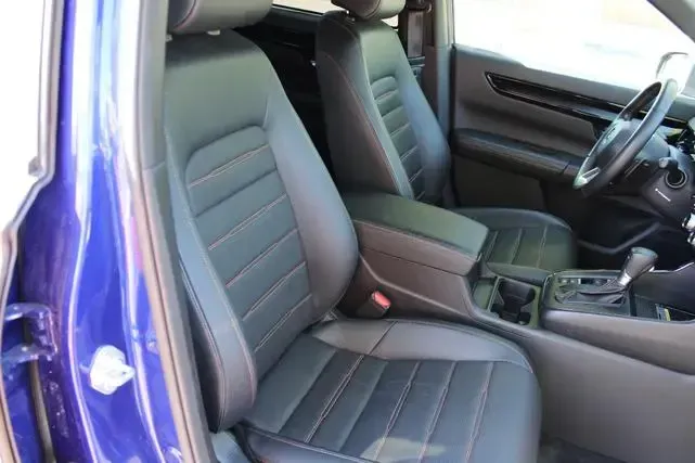 The interior of a blue car with black leather seats and a steering wheel.