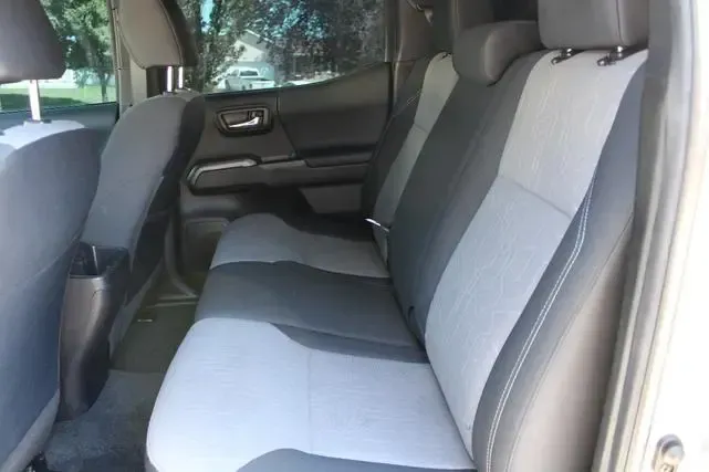 The back seat of a white truck with black and grey seats.