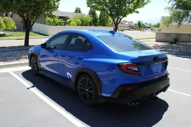 A blue subaru wrx sti is parked in a parking lot.