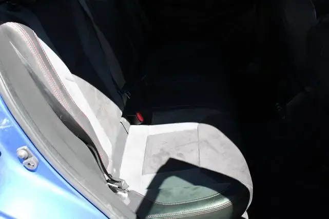 The back seat of a blue car with a seat belt on it