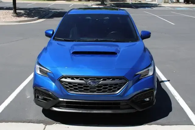 A blue subaru wrx sti is parked in a parking lot.