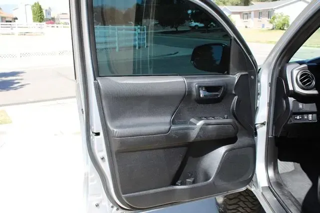 The door of a white toyota tacoma is open.