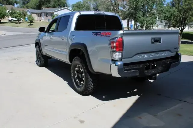 A silver toyota tacoma truck is parked in a driveway.