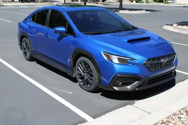 A blue subaru wrx sti is parked in a parking lot.