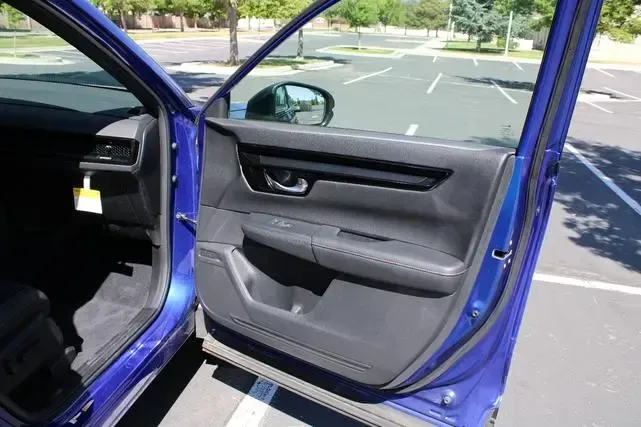 A blue car is parked in a parking lot with the door open