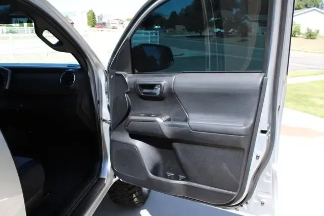 A silver car with the door open is parked on the side of the road