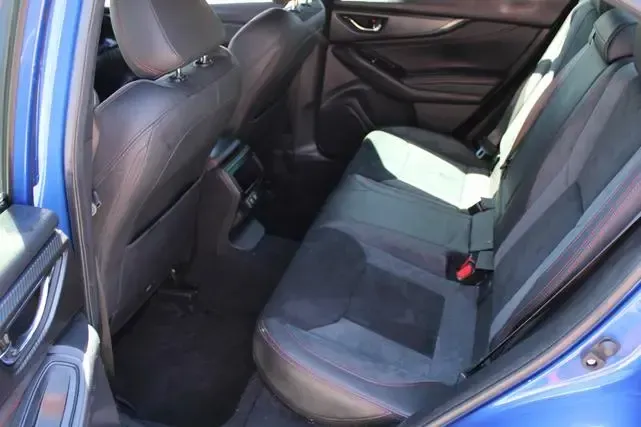 The back seat of a blue car with black seats.