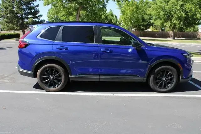A blue suv is parked on the side of the road in a parking lot.