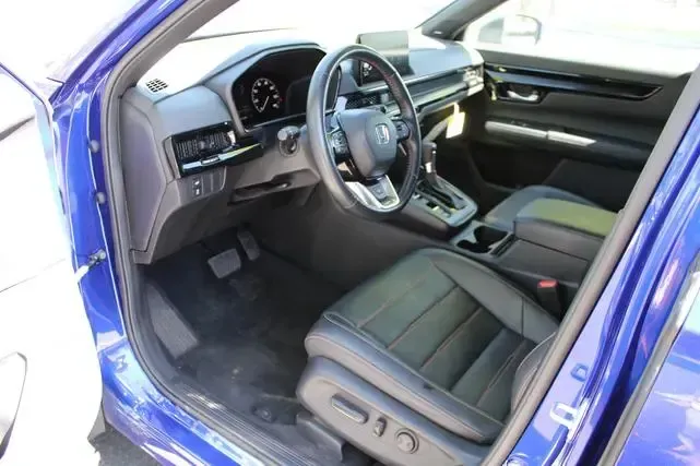 The interior of a blue car with black seats and a steering wheel.