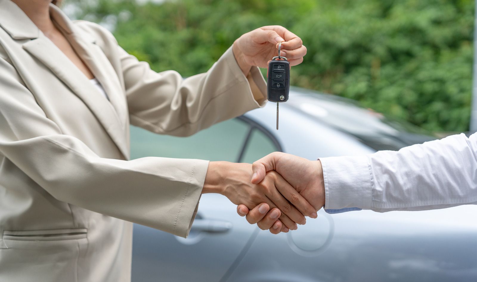 A woman is handing a car key to a man.