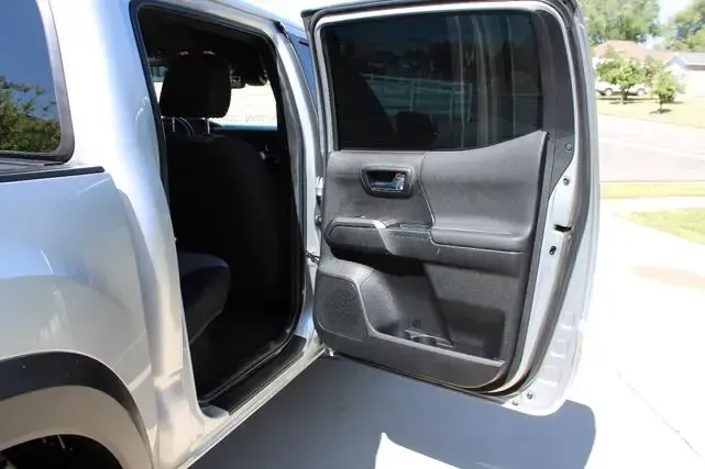 A silver truck with its doors open is parked on the side of the road.