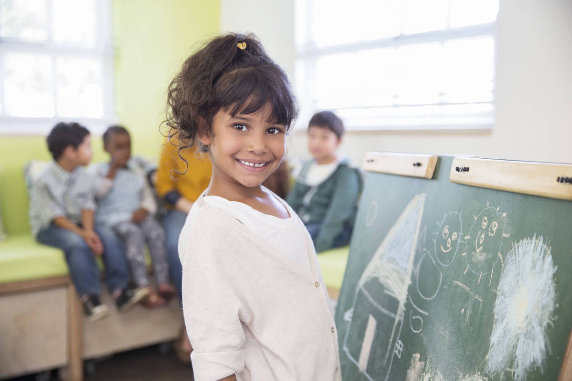 Smiling girl standing next to a chalk board