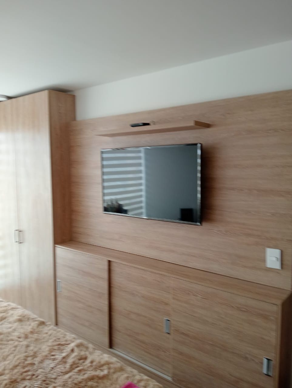 Un televisor de pantalla plana está montado en una pared de madera en una sala de estar.