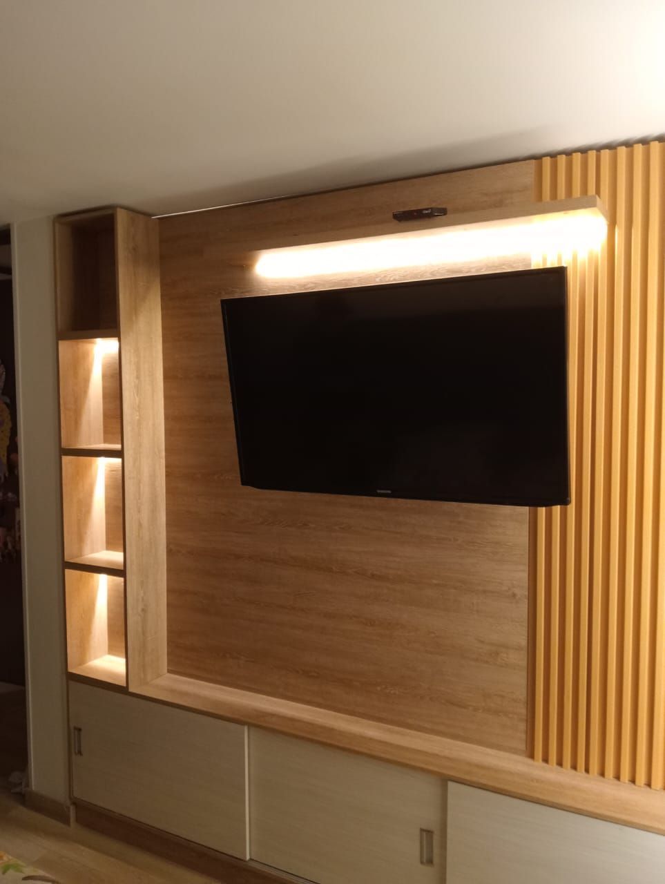 Un televisor de pantalla plana está montado en una pared de madera en una sala de estar.