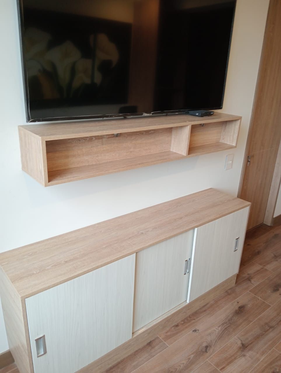 Un televisor de pantalla plana está montado en una pared de madera en una sala de estar.