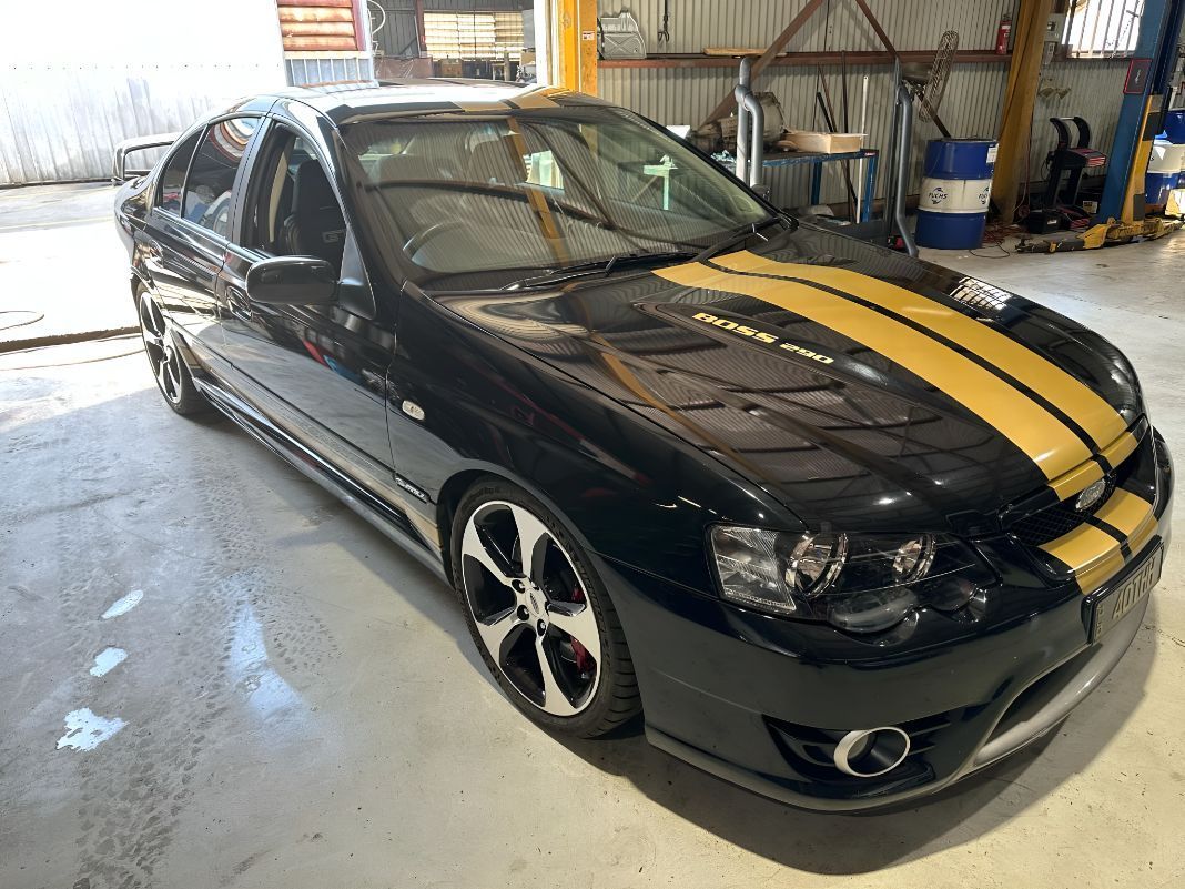 A Black Car With Yellow Stripes on the Hood is Parked in a Garage — Empire Automotive In Portsmith, QLD