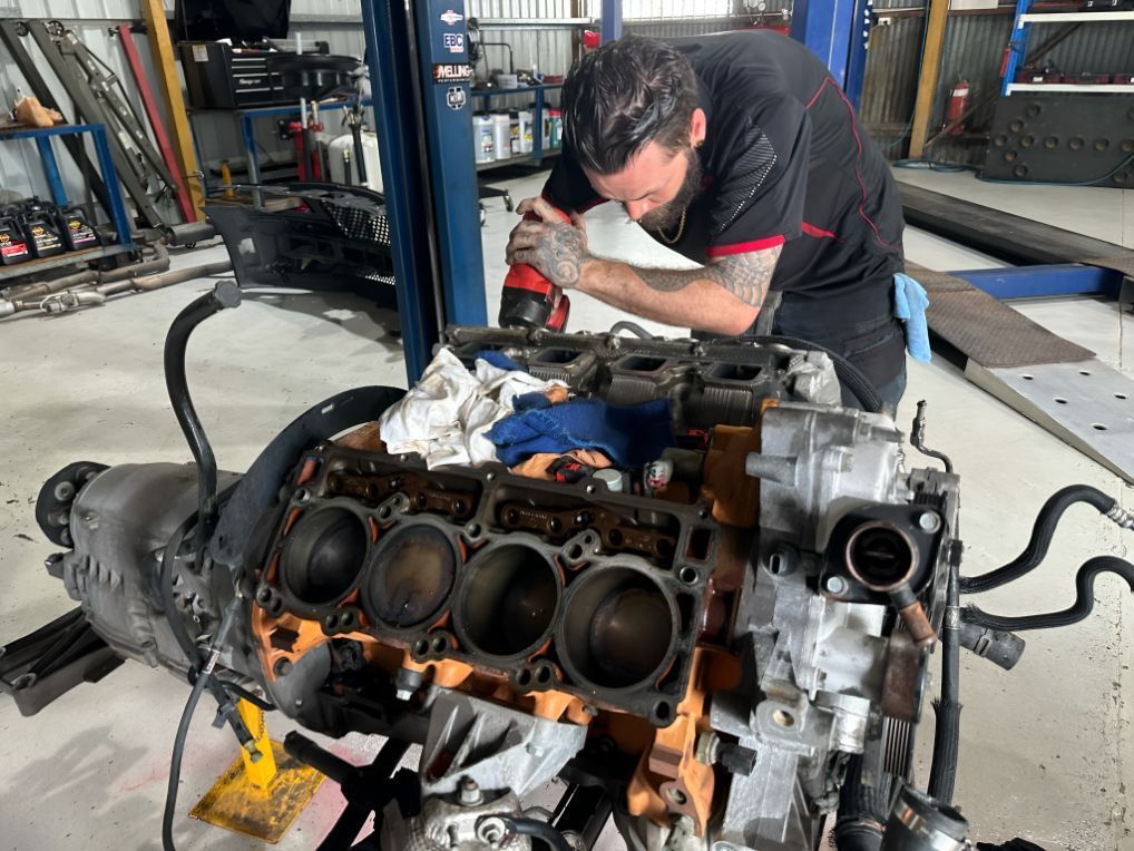 A Man is Working on a Car Engine in a Garage — Empire Automotive In Portsmith, QLD