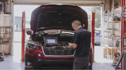 Technician analyzing under hood of red car | Andrew's Automotive Repair