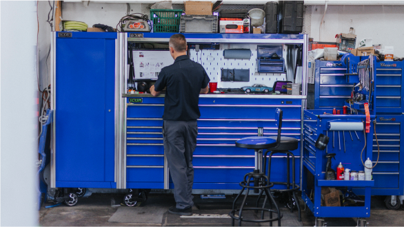 Technician working in garage with blue toolboxes | Andrew's Automotive Repair