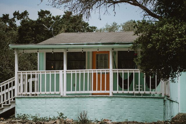 A green and orange house with a porch and stairs.