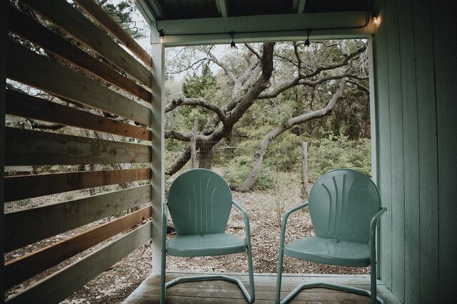 Two chairs are sitting on a porch with a view of a tree.