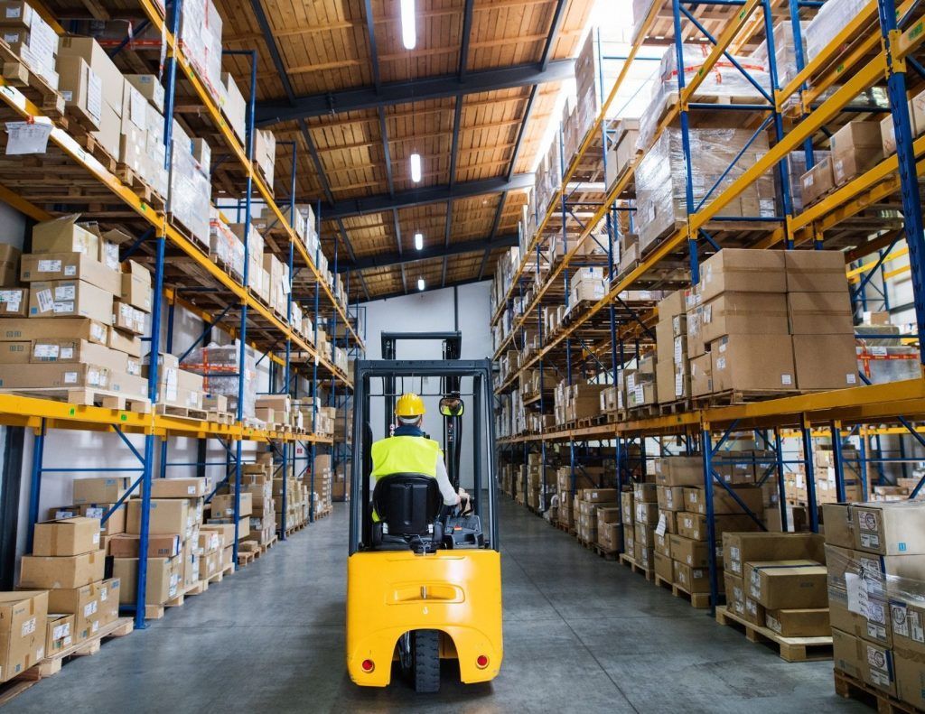 A man is driving a forklift in a large warehouse.