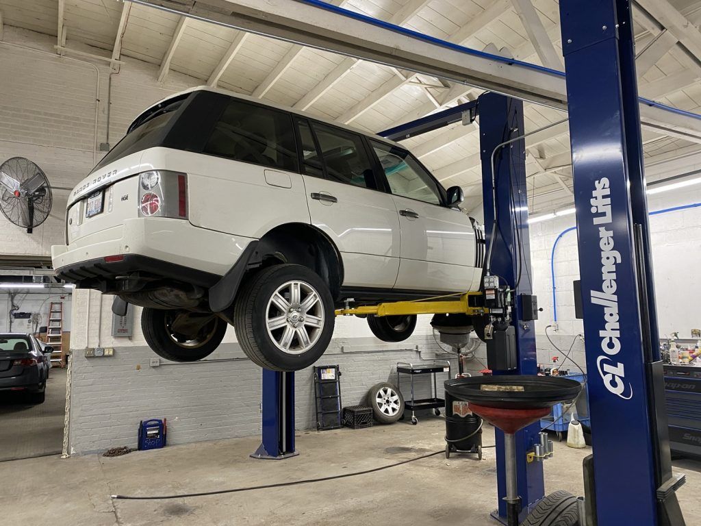 White SUV on a car lift in a garage, ready for service. | Loyola Service