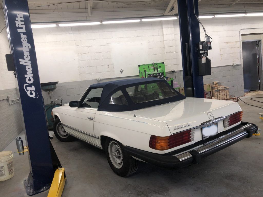 White Mercedes-Benz convertible inside a garage on a lift. | Loyola Service
