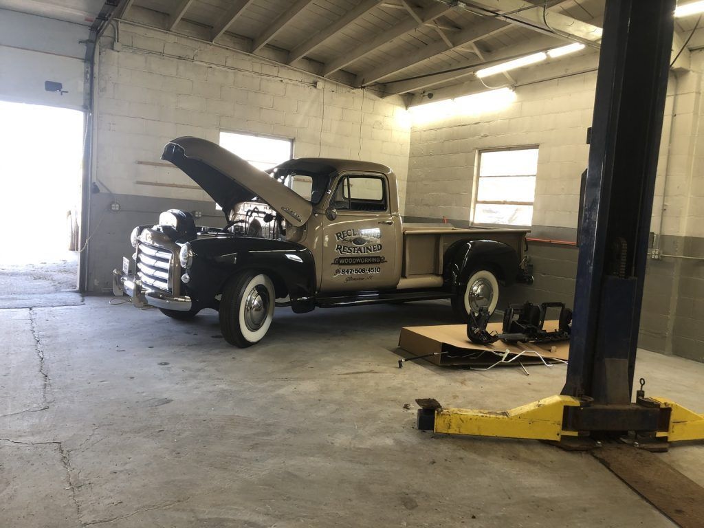 Classic black and tan pickup truck with hood open in a garage. | Loyola Service