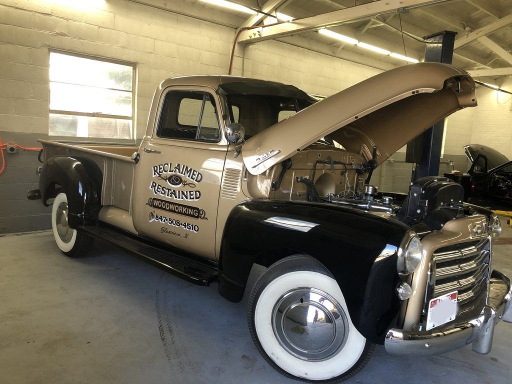 Vintage beige and black pickup truck with hood open in a garage. | Loyola Service