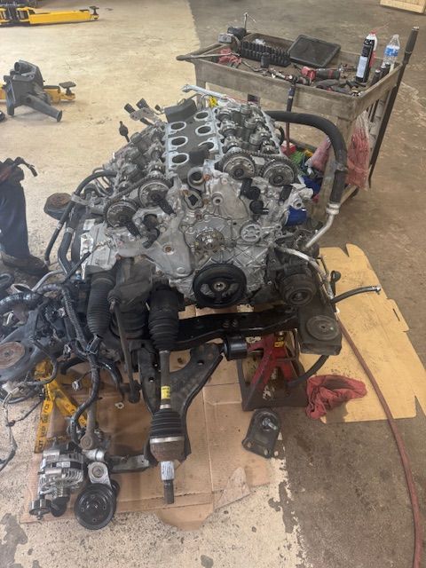 Engine on a stand, partially disassembled. Shop setting with tools and parts scattered around. | Loyola Service