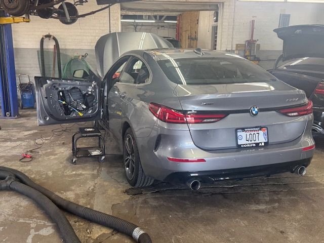Gray BMW coupe in a repair shop with the door open, revealing the interior components. | Loyola Service