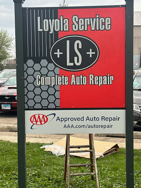 Sign for Loyola Service auto repair, red and black, with AAA approval, with a ladder in front. | Loyola Service