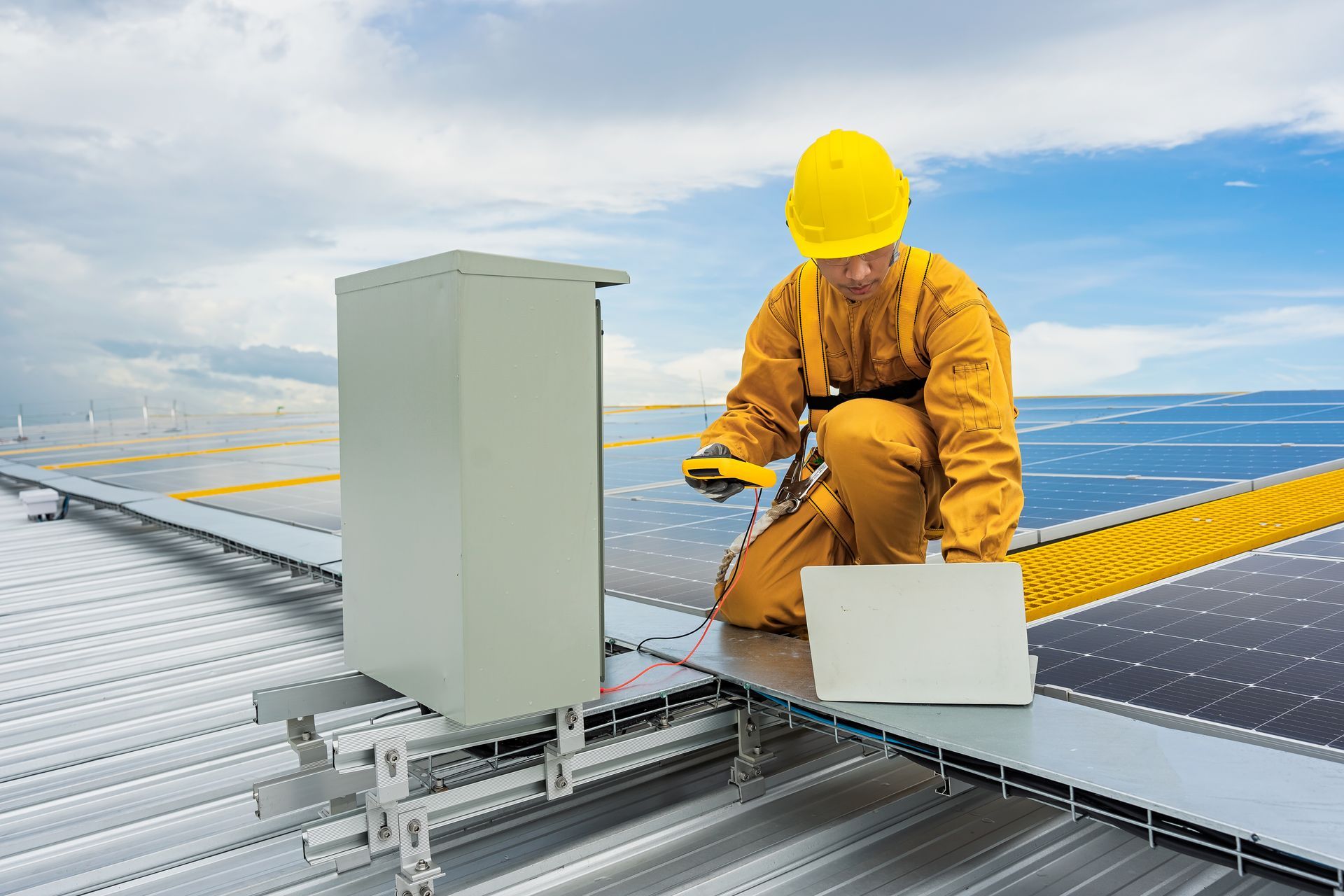 A male technician checks on an electric box placed on a roof.