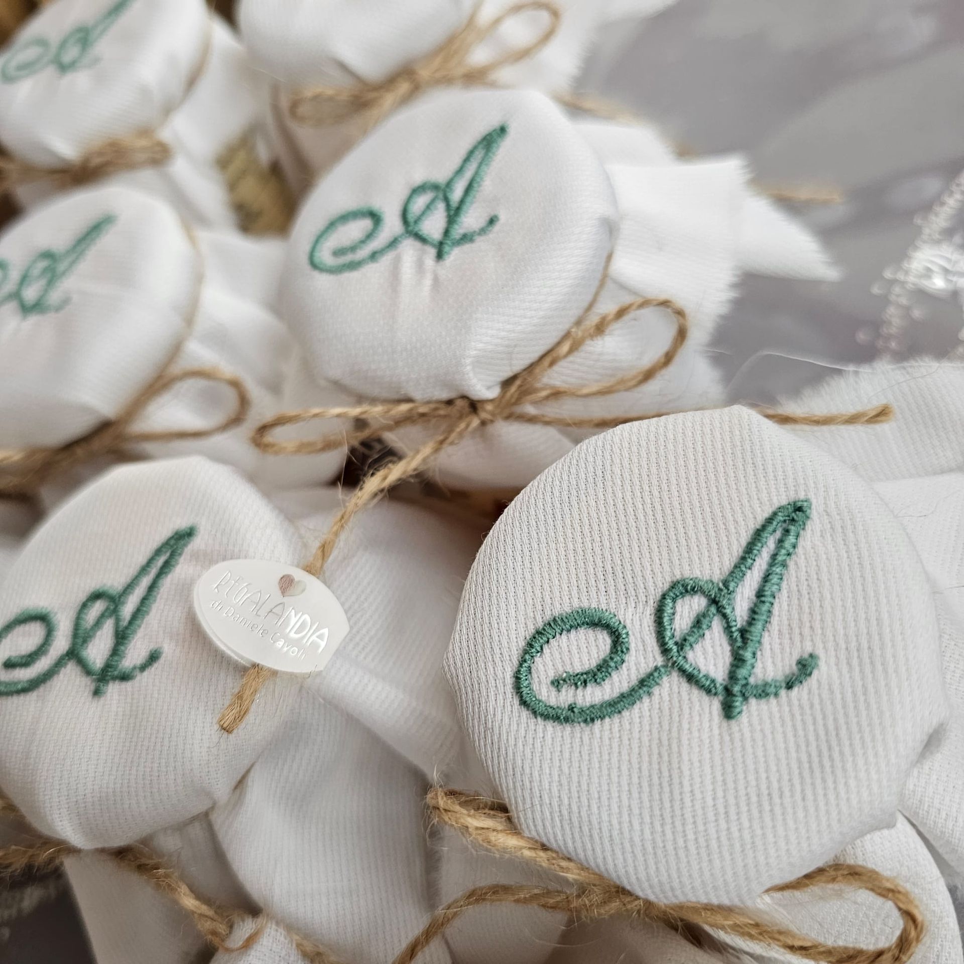 Bomboniere avvolte in tessuto bianco e legate con spago, ciascuna con una 