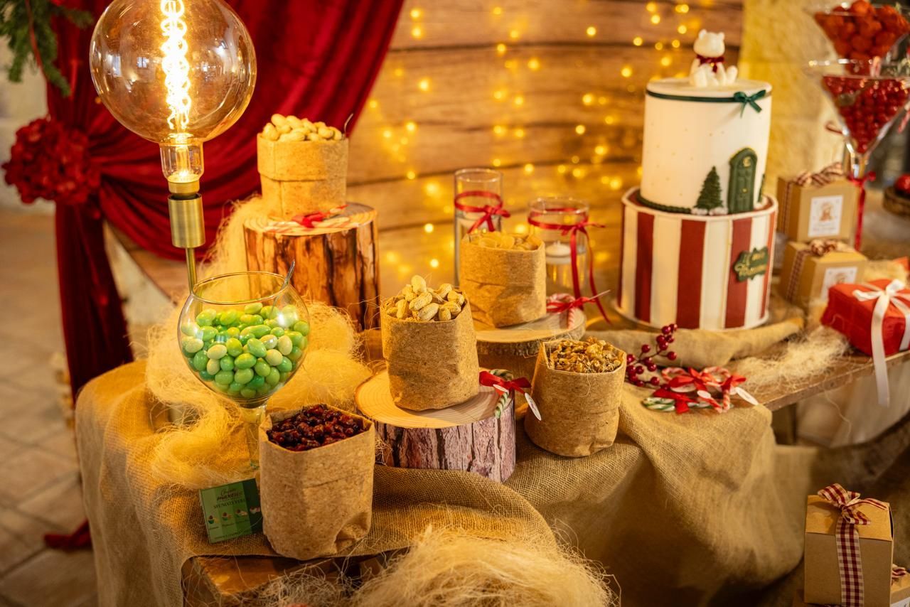 Tavolo dei dolci natalizi con torta, popcorn, caramelle e regali.