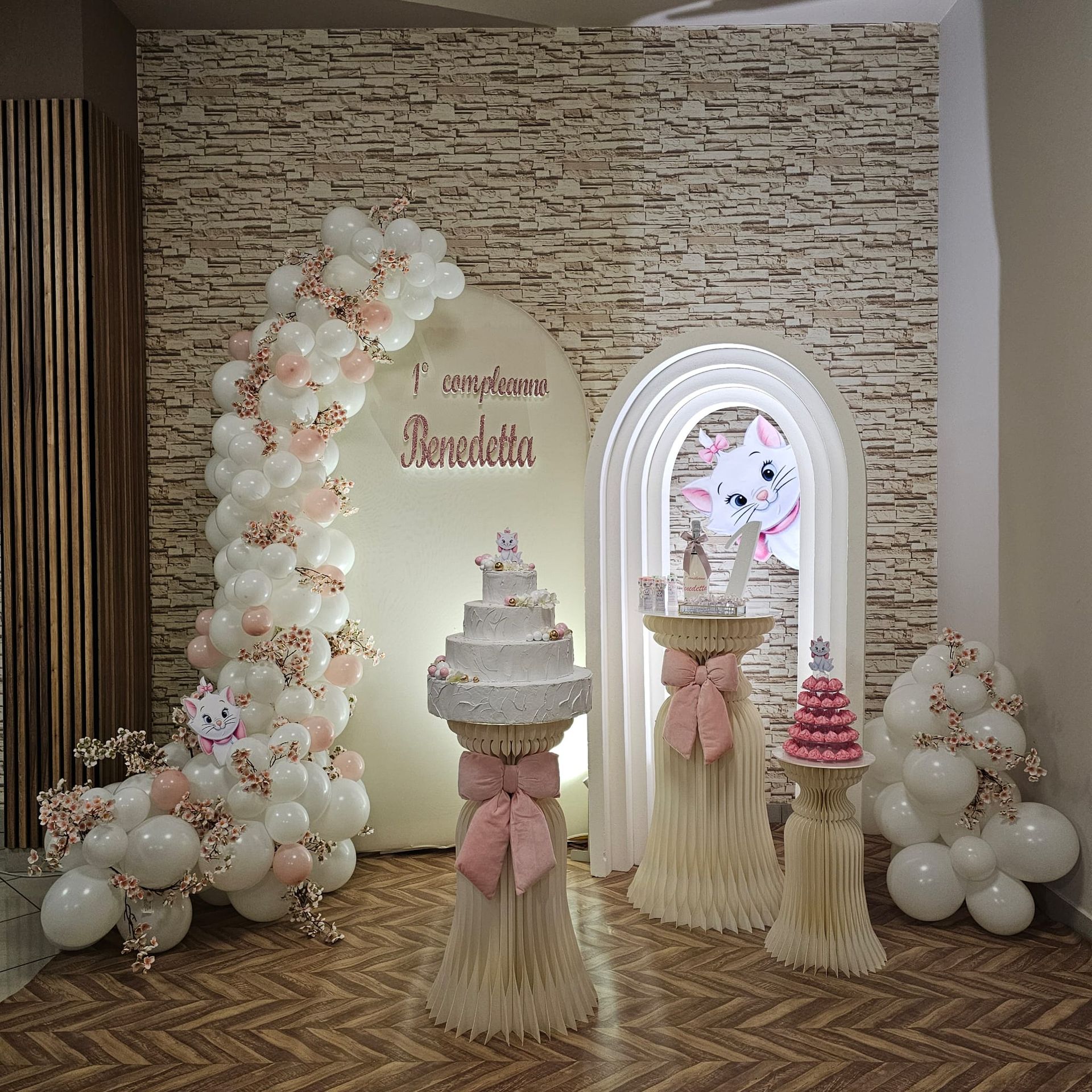Decorazioni per la festa con una torta a più piani, palloncini e il personaggio di Marie la gatta.