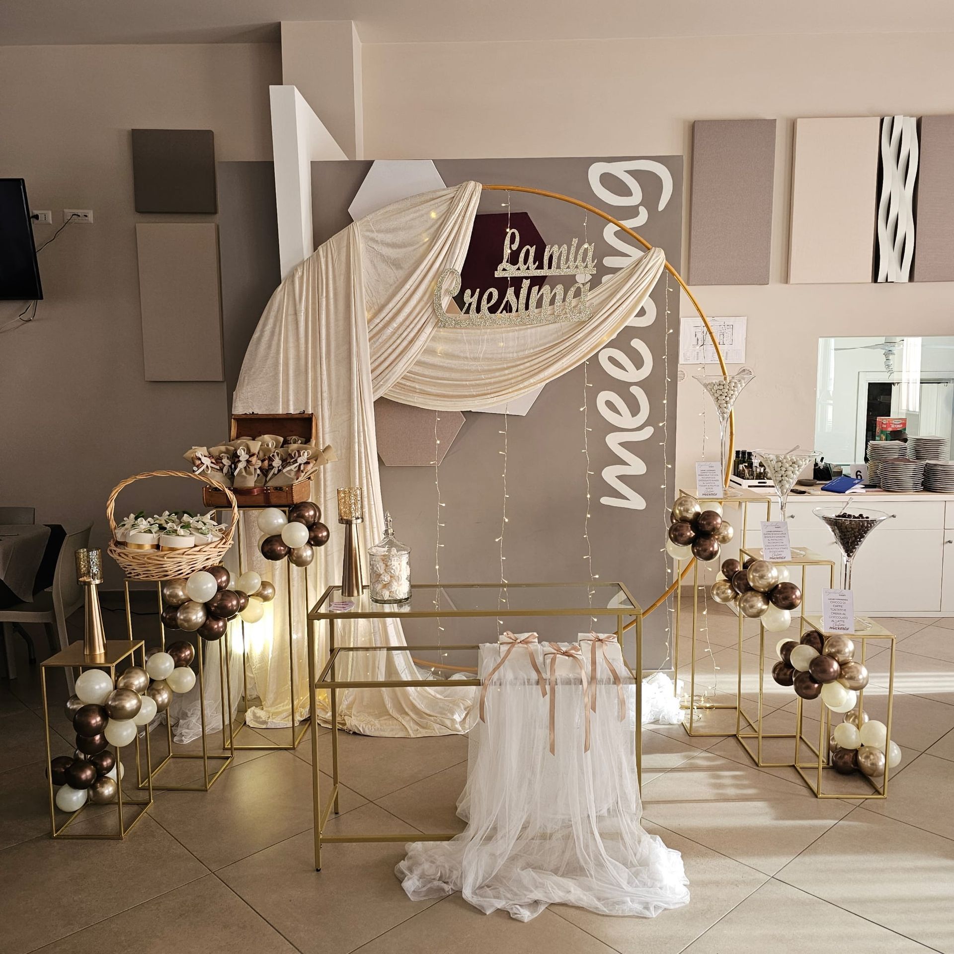 Decorazioni dorate per un evento con palloncini, fondale drappeggiato e tavoli.