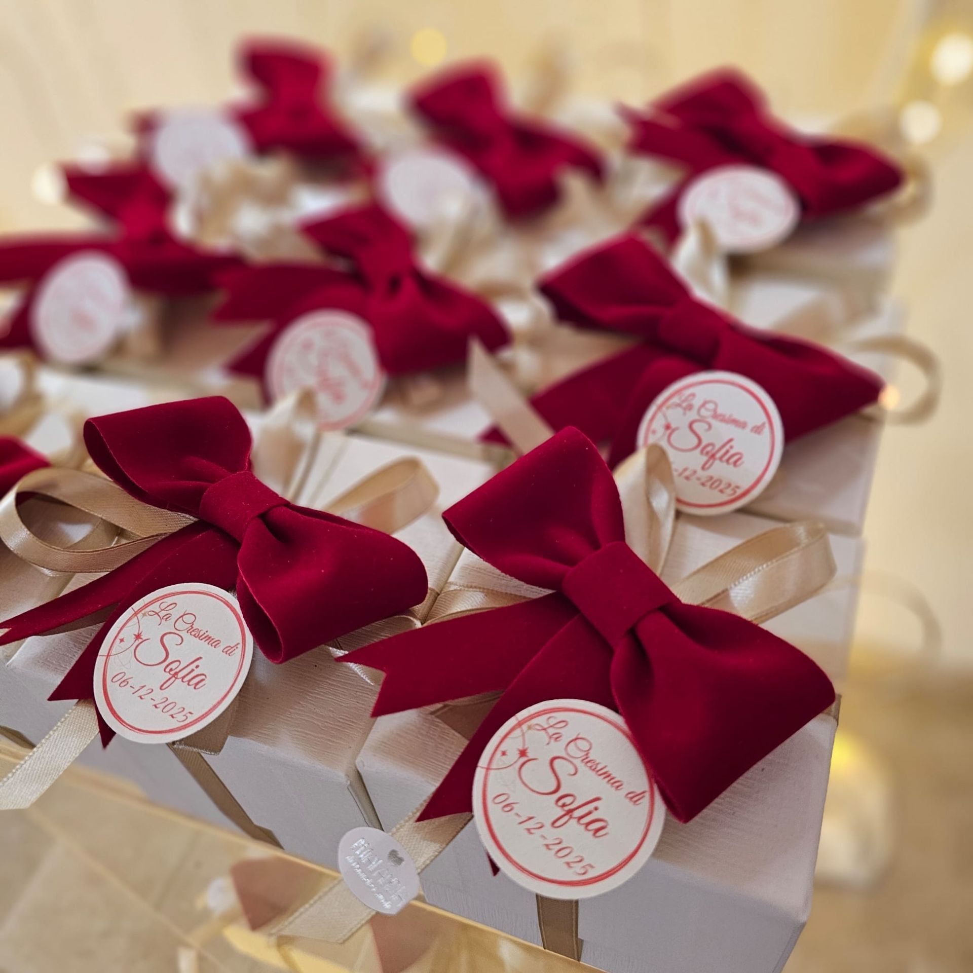 Scatole regalo bianche con fiocchi rossi ed etichette personalizzate.