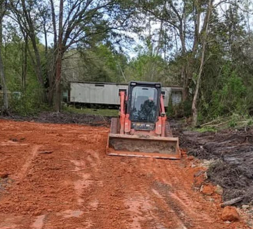 A bulldozer is moving dirt on a dirt road.