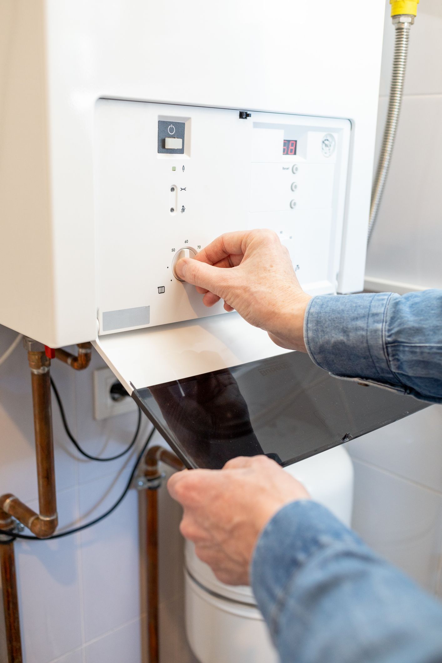 Una persona sta regolando una caldaia con una chiave inglese.