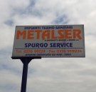 Un cartellone pubblicitario per il servizio metalser spurgo si staglia contro un cielo nuvoloso.