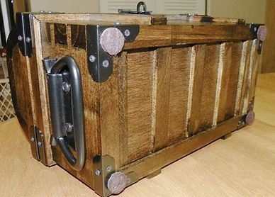 A wooden box with metal handles is sitting on a wooden table.