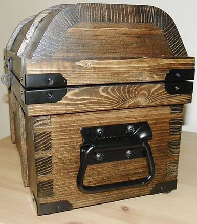 A wooden treasure chest with black handles is sitting on a wooden table