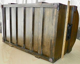 A wooden box is sitting on a table next to a ruler.