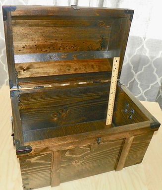 A wooden trunk with the lid open and a ruler in it.